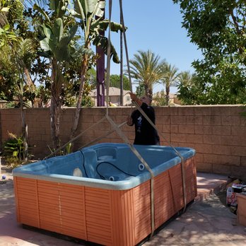 Crane lifting a spa over a wall