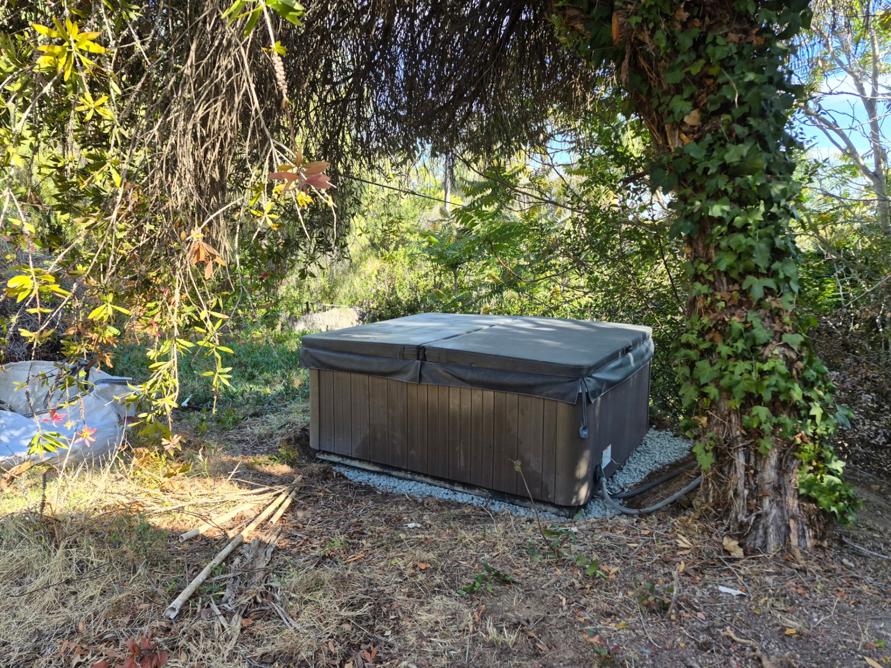 Hot tub placed on a gravel pad under trees after the Spring Valley to Bonita relocation